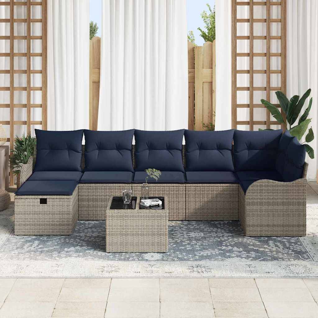Outdoor-Rattansektionalsofa mit marineblauen Kissen und passendem Couchtisch auf einem gemusterten Teppich, aufgestellt auf einer Terrasse mit Pflanzen und Vorhängen.