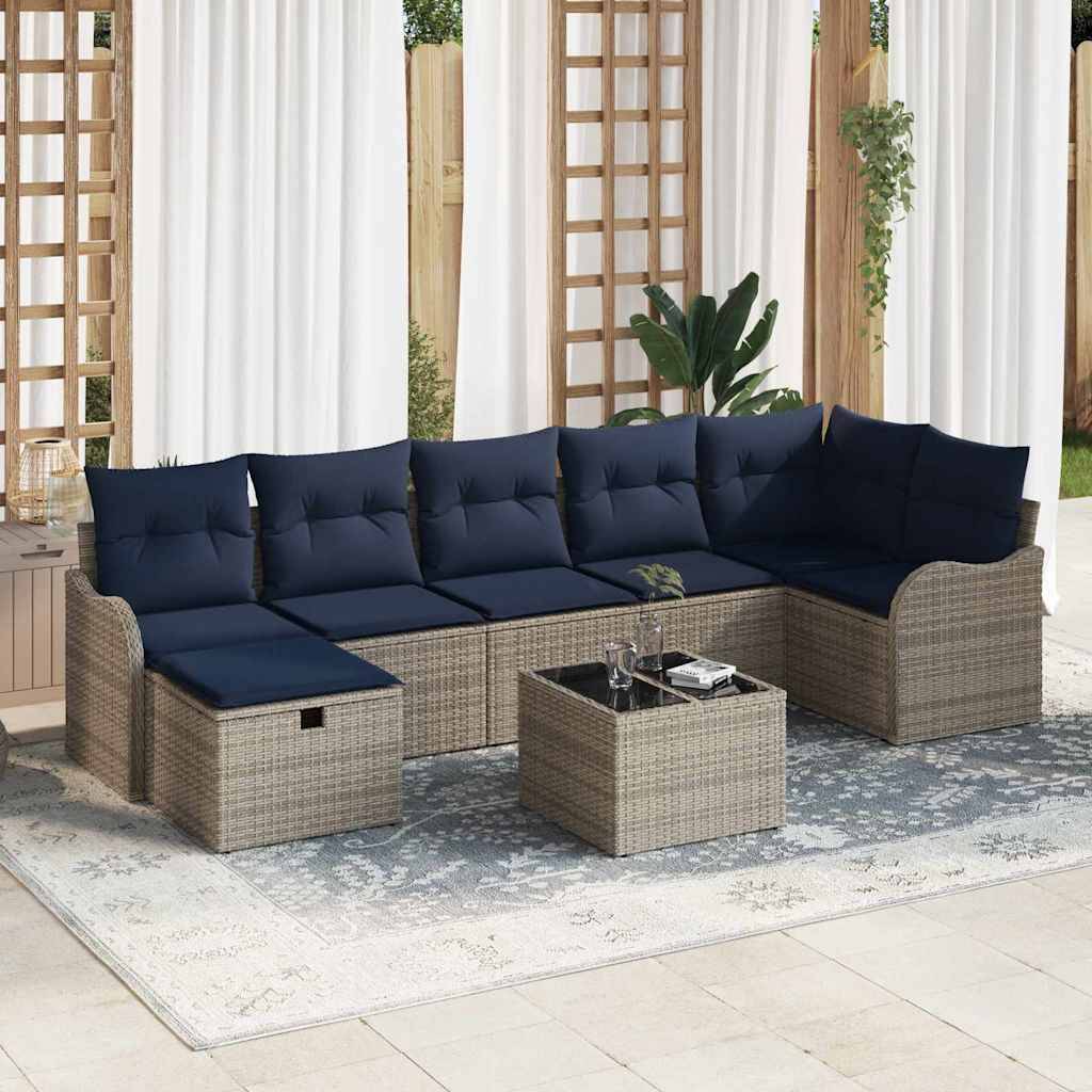 Outdoor-Rattansektionalsofa-Set mit marineblauen Kissen, passendem Ottomane und Couchtisch auf einem gemusterten Terrassenfläche in einem hellen Innen-Außen-Bereich.