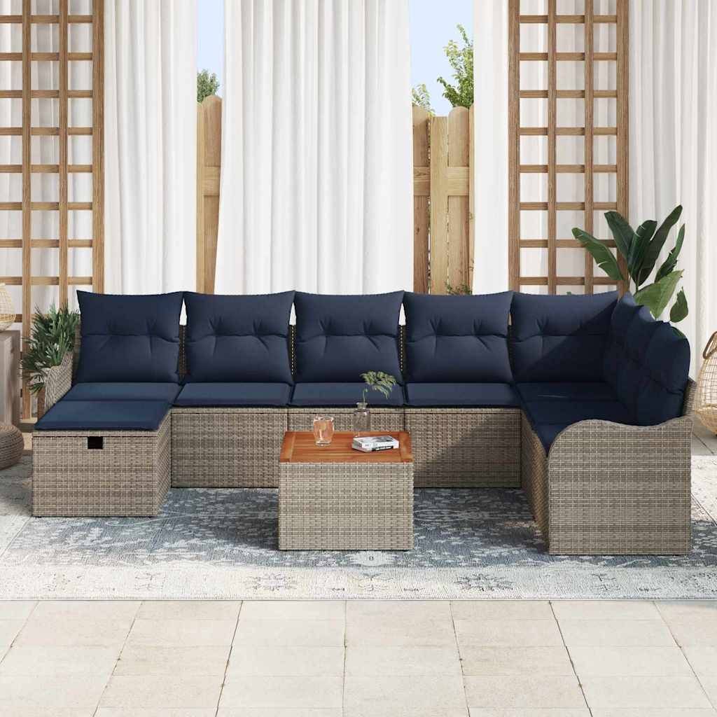 Outdoor-Terrassensektionalsofa mit marineblauen Kissen und Rattanrahmen um einen kleinen Couchtisch, vor einem Hintergrund aus Vorhängen und Pflanzen.