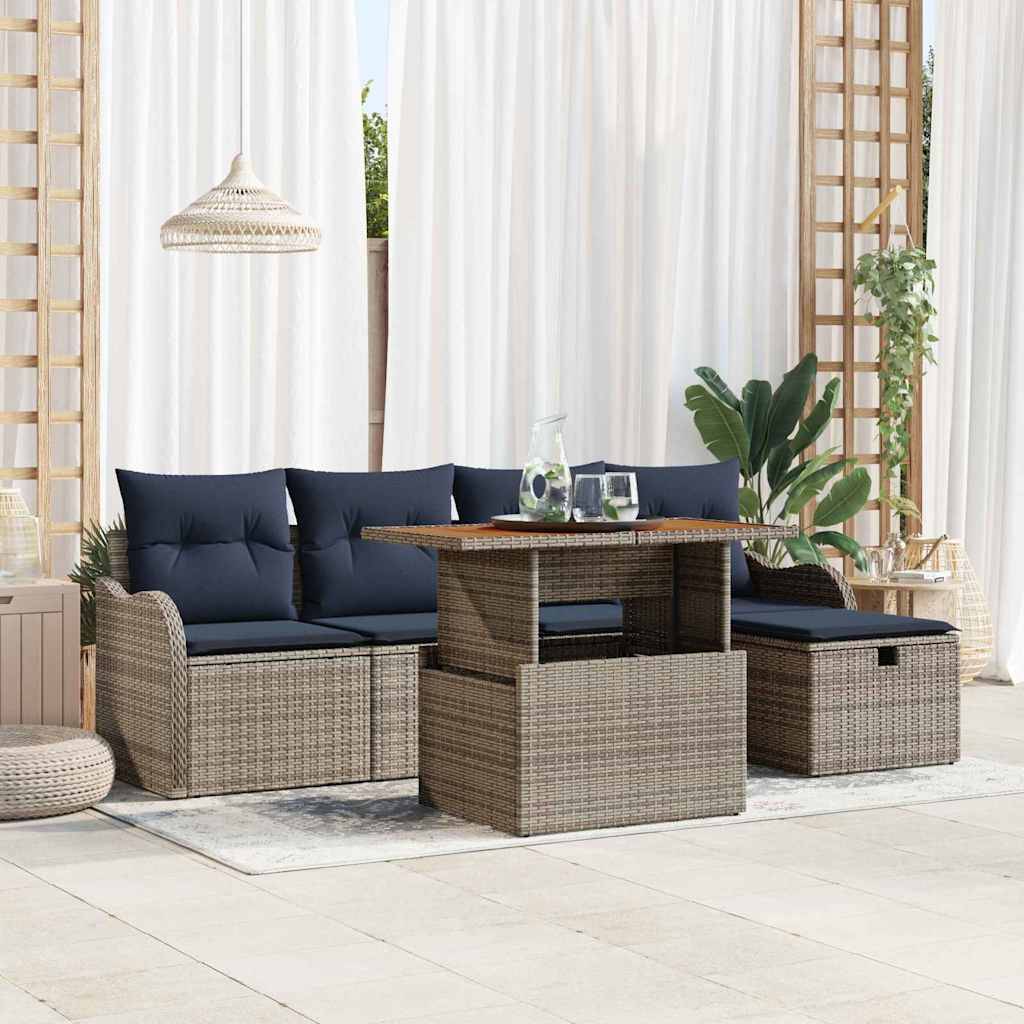 Terrassengesprächsgarnitur mit Korbsofa, Hocker und Tisch, gestylt mit dunklen Kissen und Pflanzen in einem hellen Innen-Außen-Bereich.