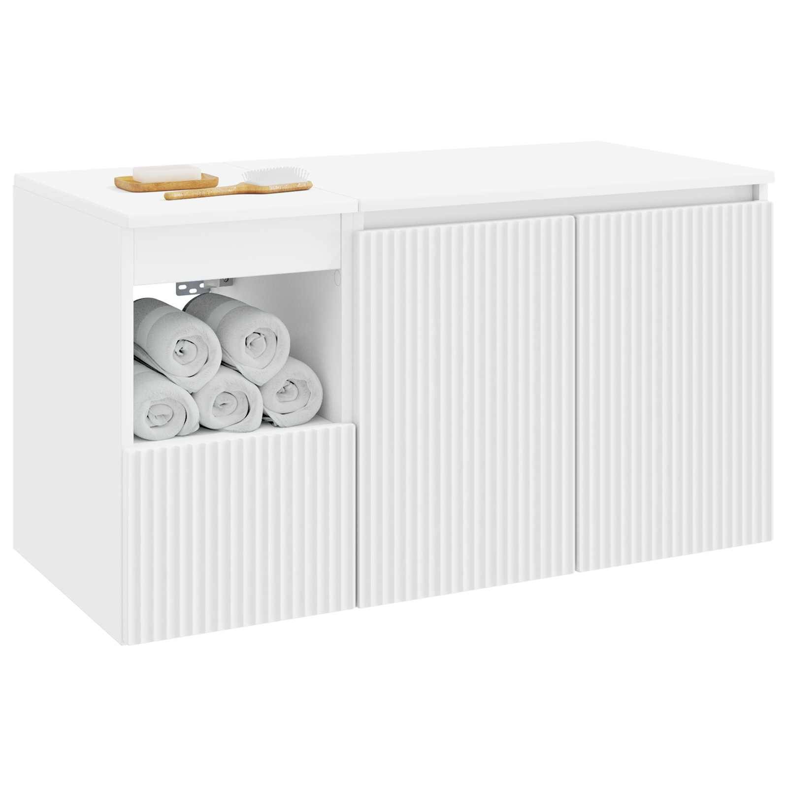 Weißer Schrank mit Rippen, zwei Türen und offenes Regal mit aufgerollten Handtüchern; Holztablett oben.
