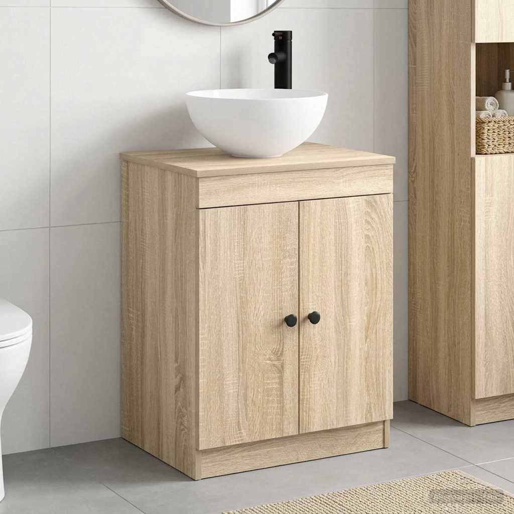 Badezimmer-Waschtischschrank aus hellem Holz mit Doppeltüren und weißem Aufsatzwaschbecken, dargestellt in einem modernen Badezimmer neben einer Toilette und einer passenden Aufbewahrungseinheit.