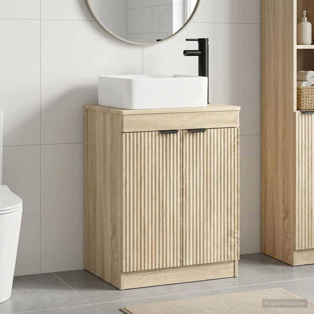 Modernes Badezimmerwanteleau mit weißem Aufsatzwaschbecken und schwarzem Wasserhahn auf einem Unterschrank aus hellem Holz, gezeigt neben einem runden Spiegel und einer gefliesten Wand.