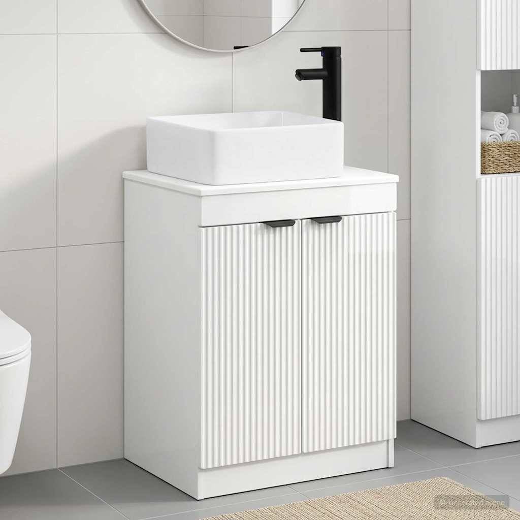 Modernes weißes Badezimmer-Waschtischset mit gerippten Schranktüren, Aufsatzwaschbecken und schwarzem Wasserhahn vor gefliesten Wänden.