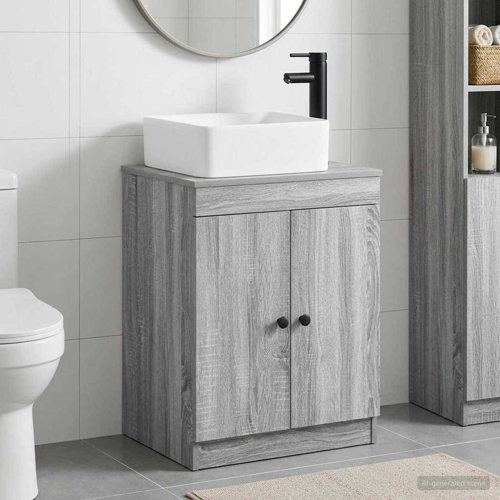 Moderner Badezimmerschrank mit weißem Aufsatzwaschbecken und schwarzem Wasserhahn neben einer Toilette, gezeigt in einem grau gekachelten Badezimmer.