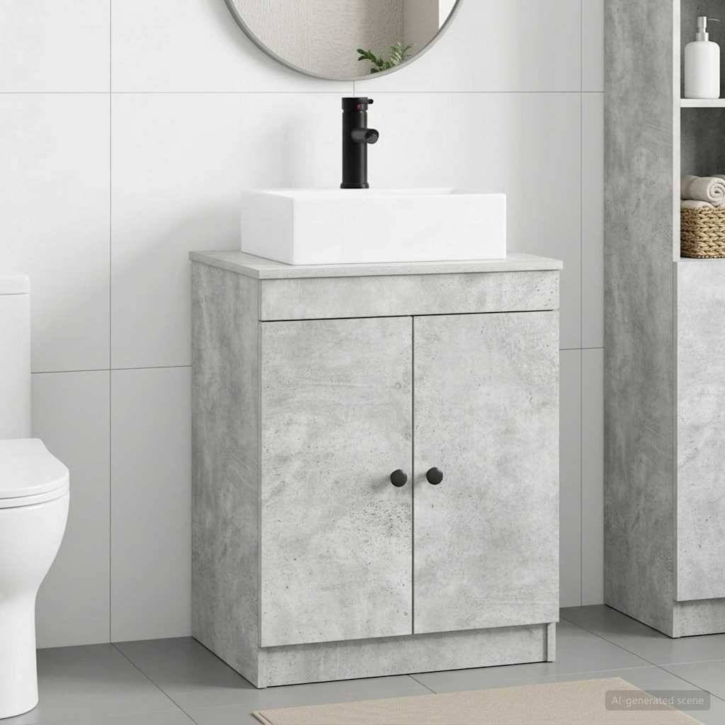 Modernes Badezimmerwaschbecken mit betonoptimiertem Schrank, weißem rechteckigem Waschbecken, schwarzem Wasserhahn, rundem Spiegel darüber und teilweise sichtbarer Toilette auf der linken Seite.