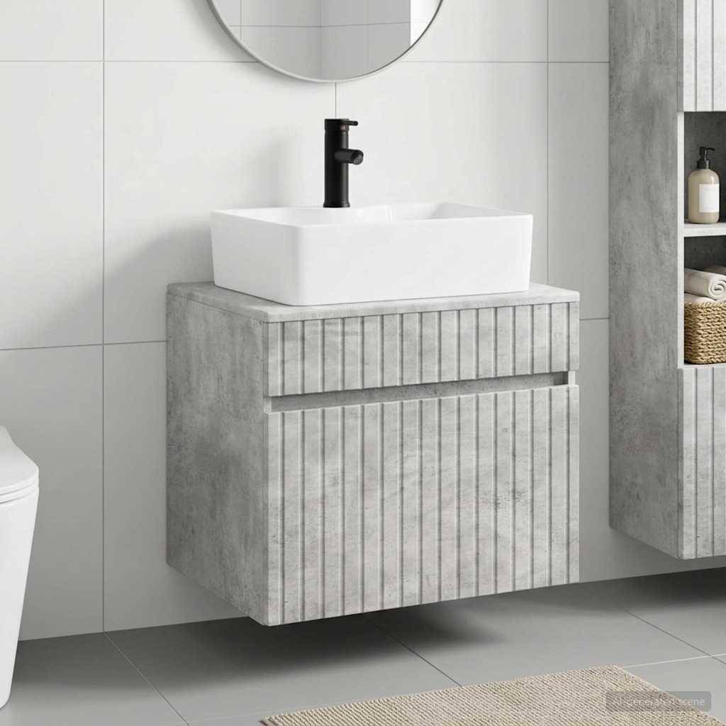 Modernes Badezimmer-Waschtisch mit weißem Aufsatzwaschbecken und schwarzem Wasserhahn auf einem grauem Betonoptik-Unterschrank, daneben ein passender Wandschrank.
