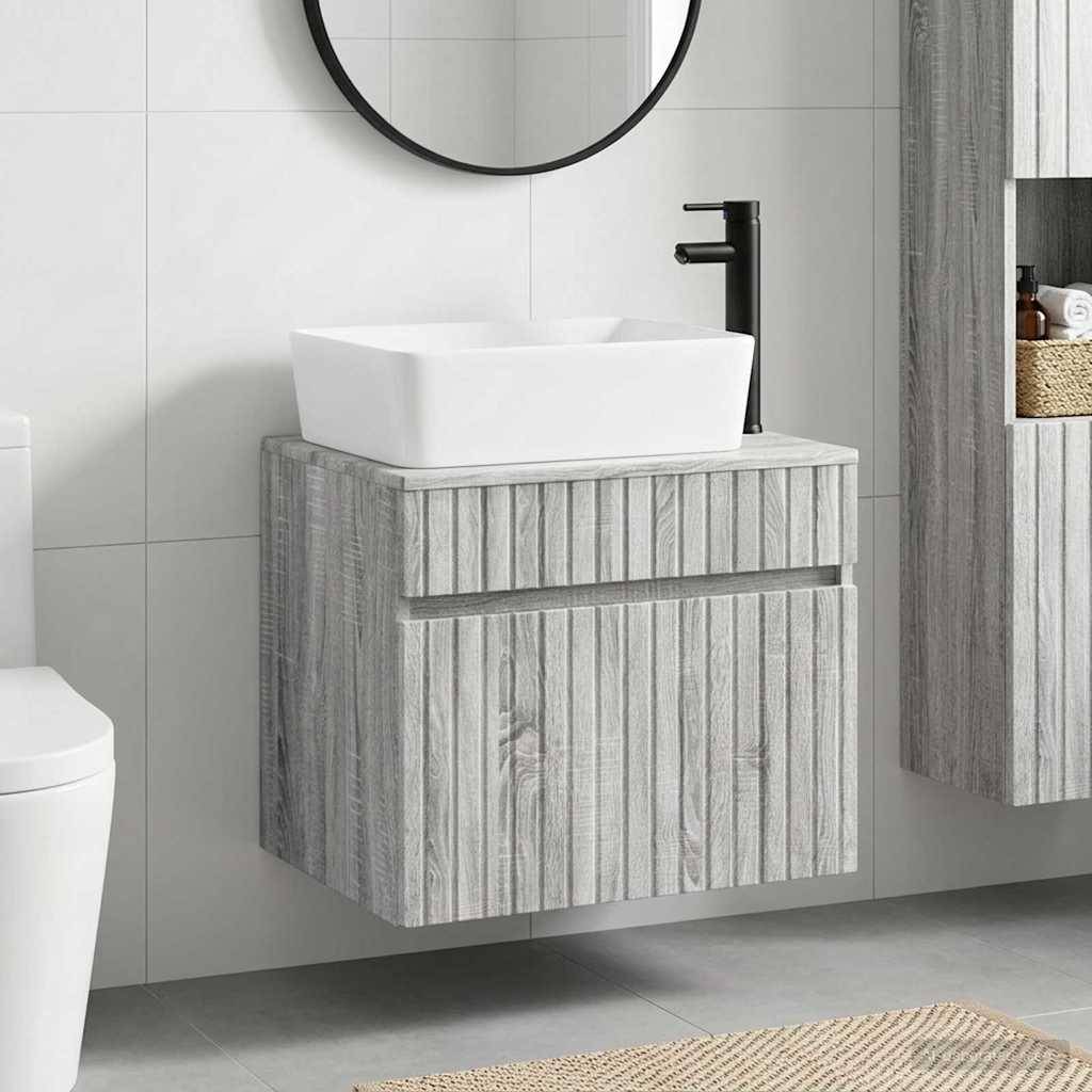 Modernes Badezimmerwaschtisch mit weißem Aufsatzwaschbecken, schwarzem Wasserhahn, rundem Spiegel und hellem Holzschrank vor geflieseter Wand