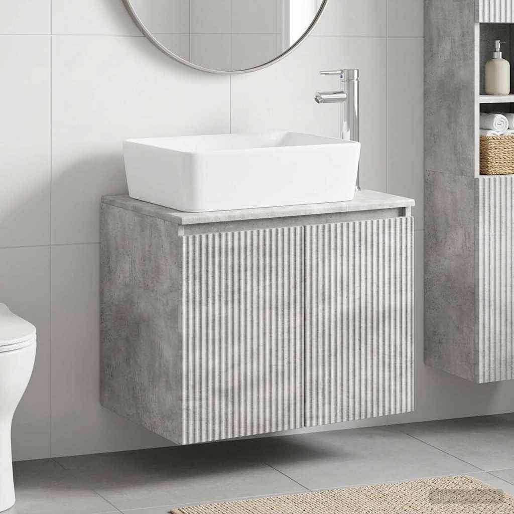 Modernes Badezimmer-Waschtisch mit weißem Aufsatzwaschbecken und Chromarmatur auf einem grauen Schrank mit gerippten Frontpaneelen, neben einem Spiegel und Regalen.