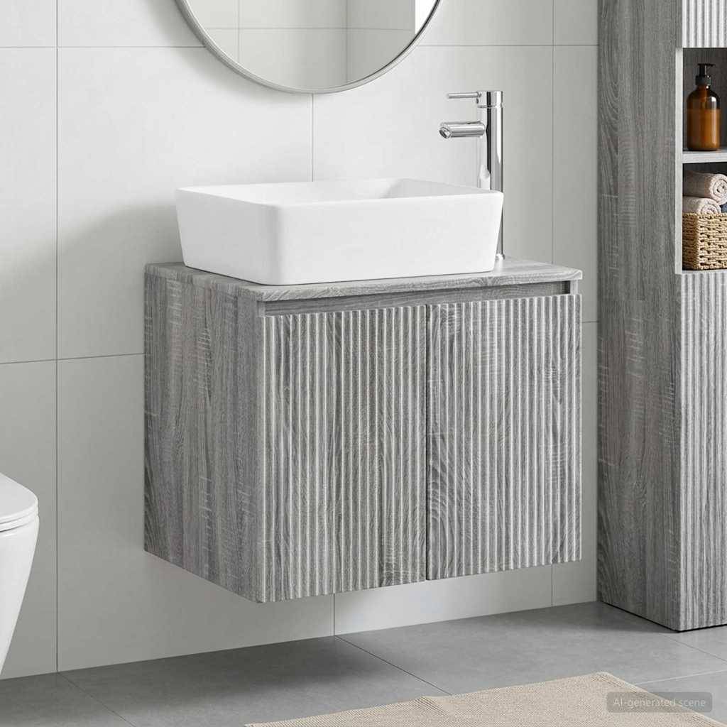 Modernes Badezimmerwaschtisch mit weißem Aufsatzwaschbecken, wandmontiertem Wasserhahn und grauem Holzmaserungschrank; Spiegel und Regale daneben.