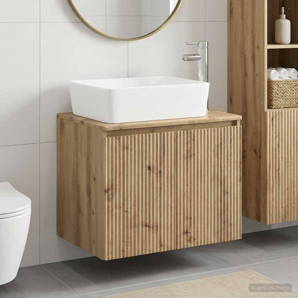 Modernes Badezimmer-Waschtisch mit weißem Aufsatzwaschbecken auf einem gerilltem Holzschrank, neben einem Spiegel und wandmontiertem Wasserhahn.
