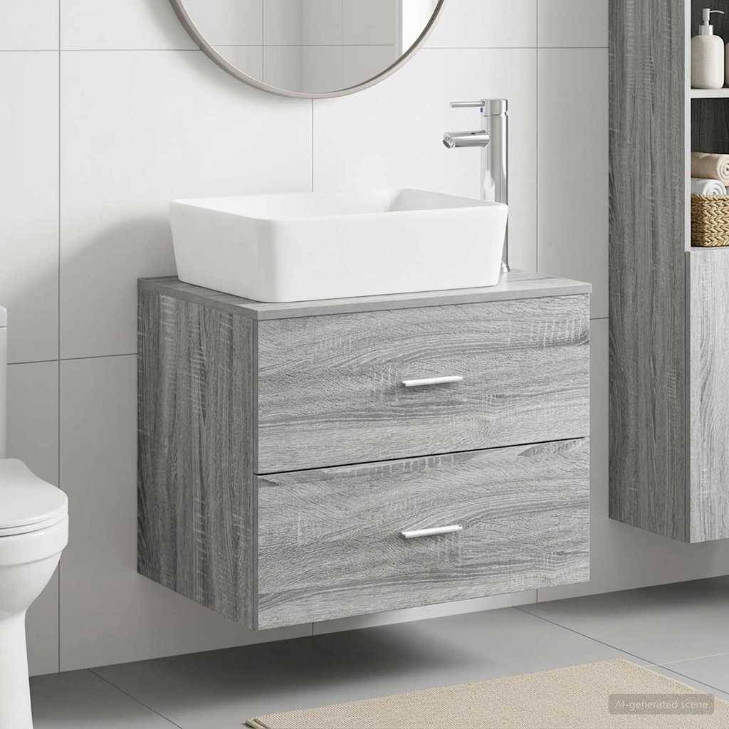 Grau getönte Badezimmerkommode mit zwei Schubladen und weißem Aufsatzwaschbecken, an einer gefliesten Wand montiert, mit rundem Spiegel darüber.