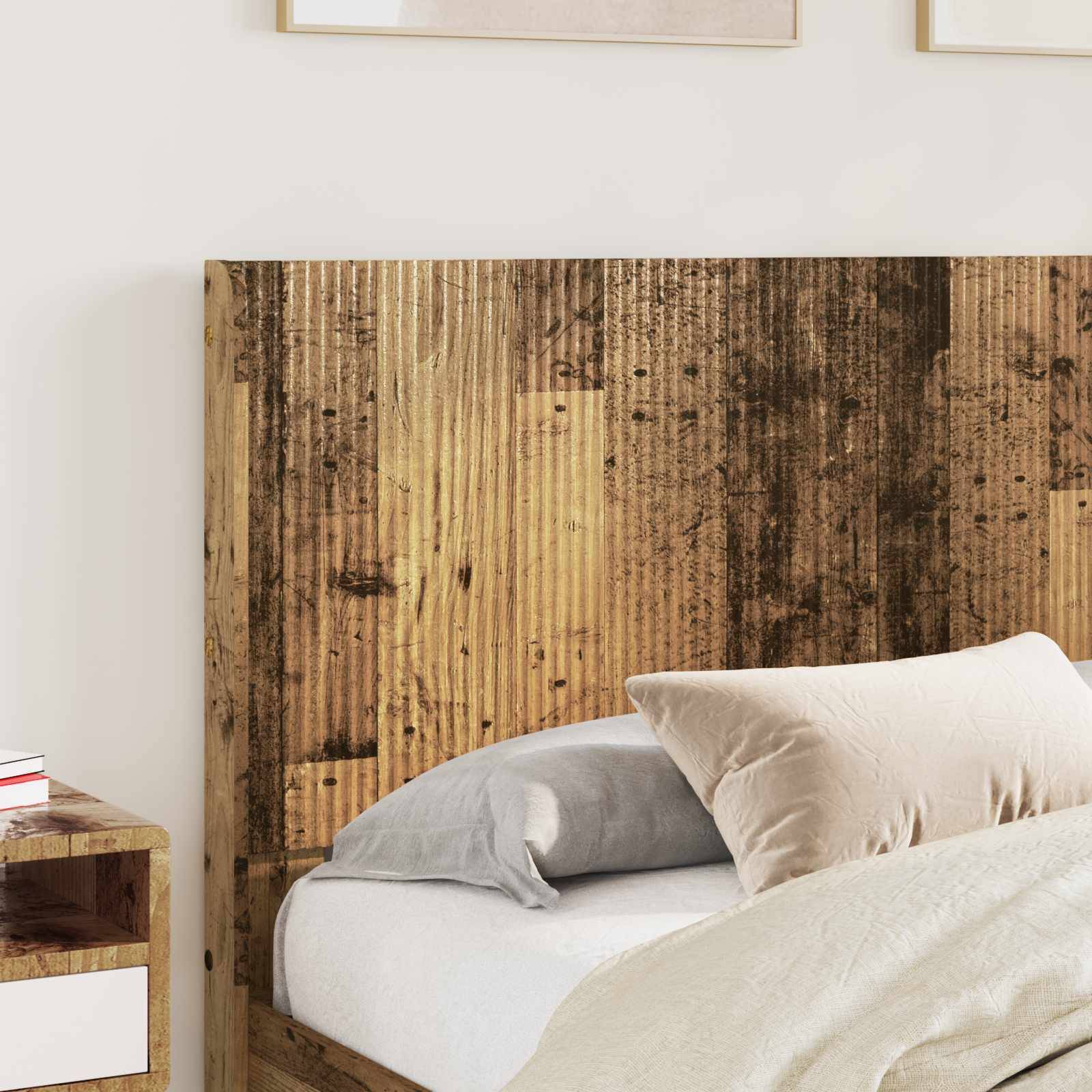 Bett mit weißen und grauen Kissen vor einem rustikalen Holzkopfteil, mit einem kleinen Nachttisch daneben.