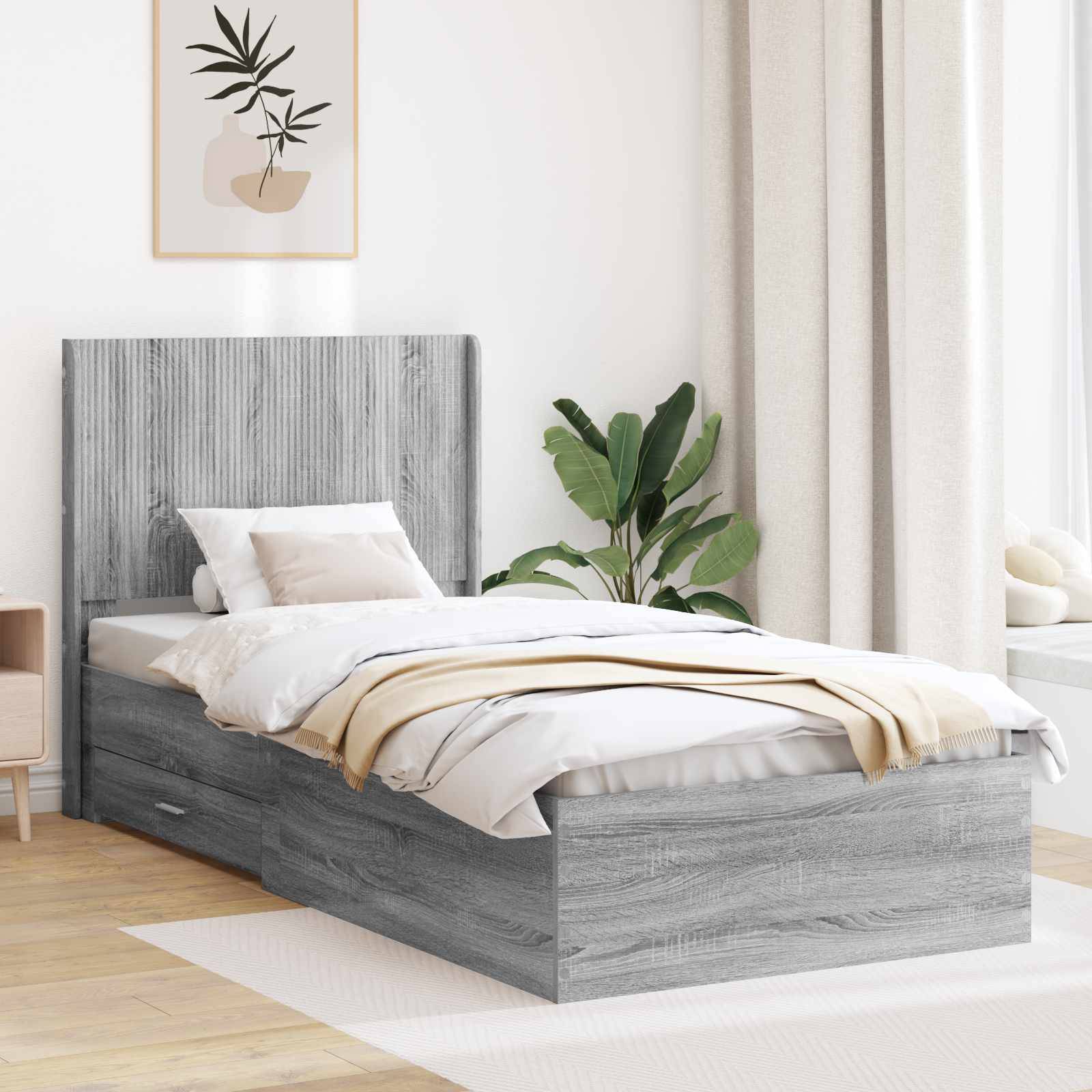 Modernes graues gepolstertes Einzelbett in einem hellen, minimalistischen Schlafzimmer mit weißer Bettwäsche, beigem Plaid, Pflanze und Wandkunst.