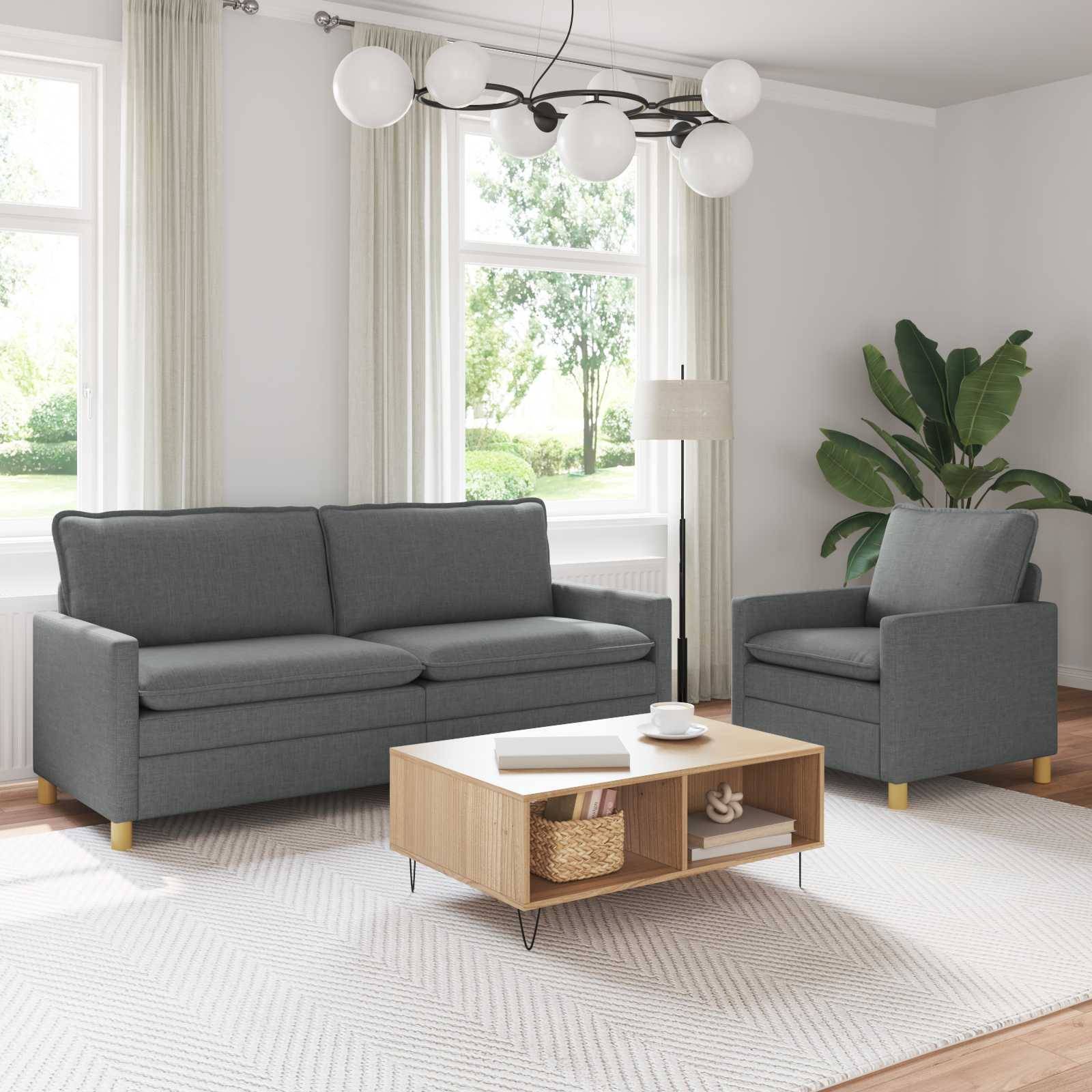 Modernes Wohnzimmer mit grauem Sofa und Sessel, hellem Holz-Couchtisch, großen Fenstern, Stehlampe, Pflanze und gemustertem Teppich.