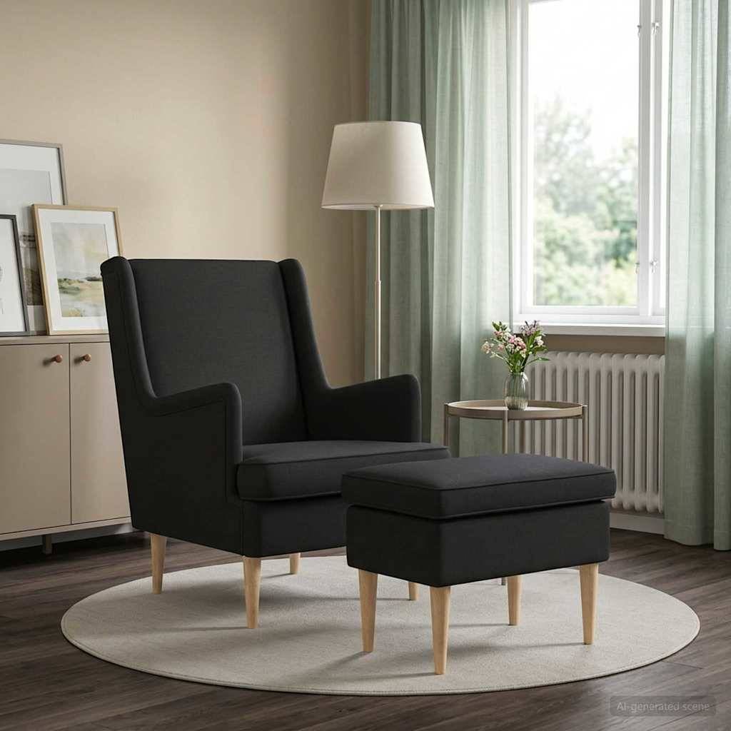 Schwarzer Flügelsessel mit passendem Hocker in einem hellen Wohnzimmer neben einem Fenster, einer Lampe, einem Beistelltisch und einem Wandbild in Rahmen.