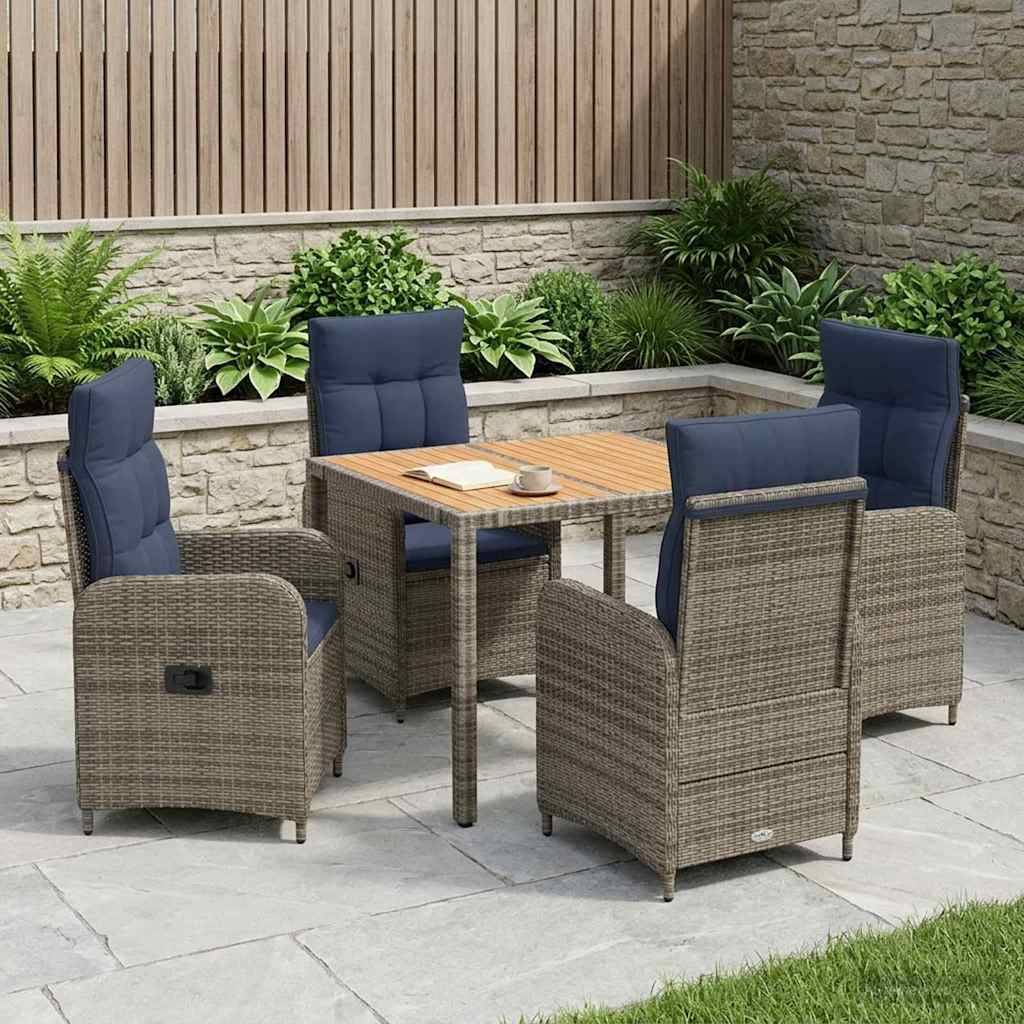 Gartenmöbel-Set im Freien mit vier gepolsterten Rattanstühlen um einen quadratischen Tisch, auf einer Steinplattform neben einem gestalteten Garten und einer Steinmauer.