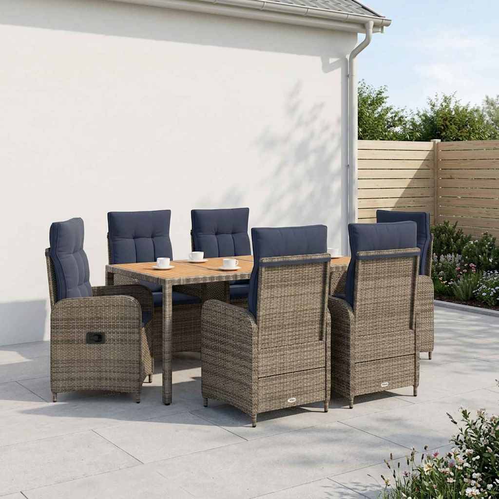 Essbereich auf der Terrasse im Freien mit sechs geflochtenen Sesseln um einen quadratischen Tisch, vor einer weißen Hauswand und eingezäuntem Garten.