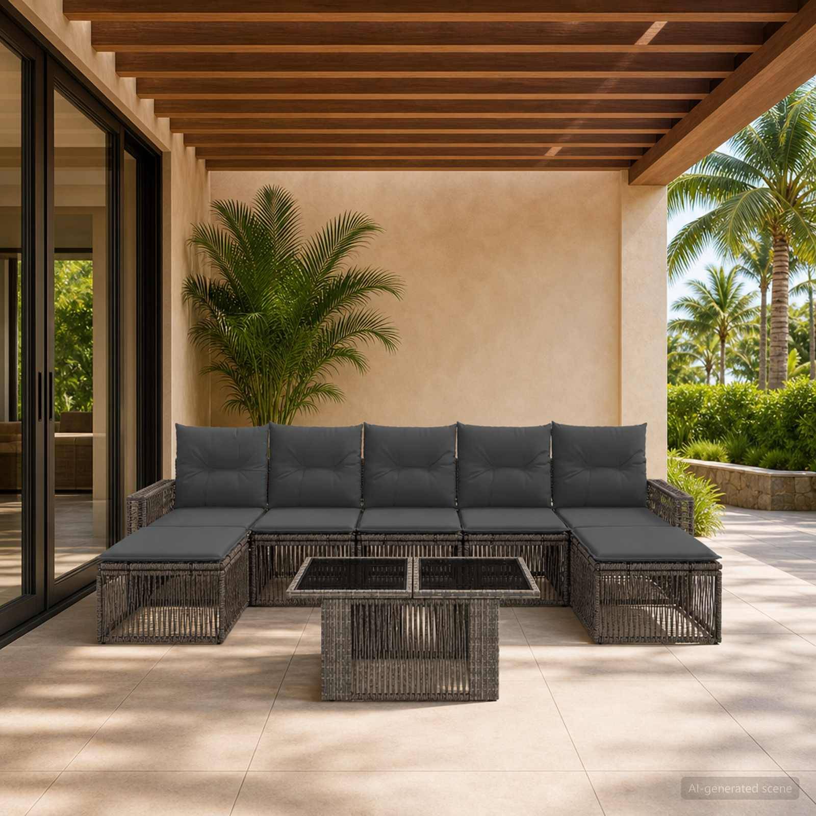Überdachte Terrasse mit dunklem Rattansektionalsofa und Couchtisch mit Blick auf einen sonnigen tropischen Garten mit Palmen.