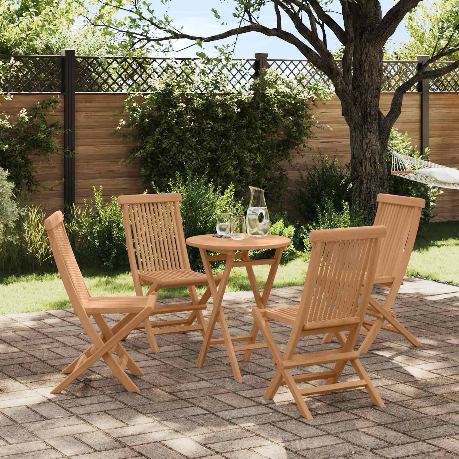Vier Holzgartenstühle um einen kleinen runden Tisch mit einem Krug und Gläsern auf einer sonnigen Ziegelpflaster-Terrasse in einem Hintergartenbereich.