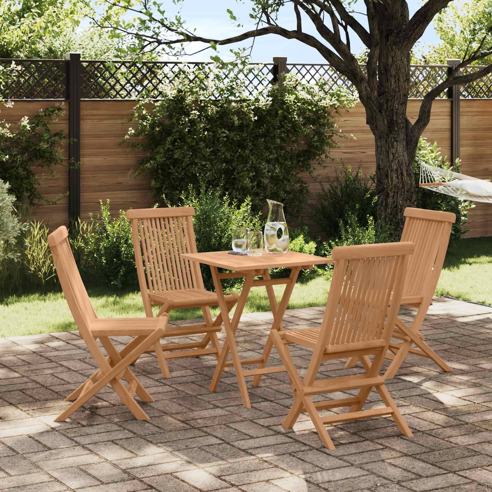 Gartengarnitur im Freien mit vier zusammenklappbaren Holzstühlen um einen kleinen quadratischen Tisch auf einer gepflasterten Terrasse unter einem Baum