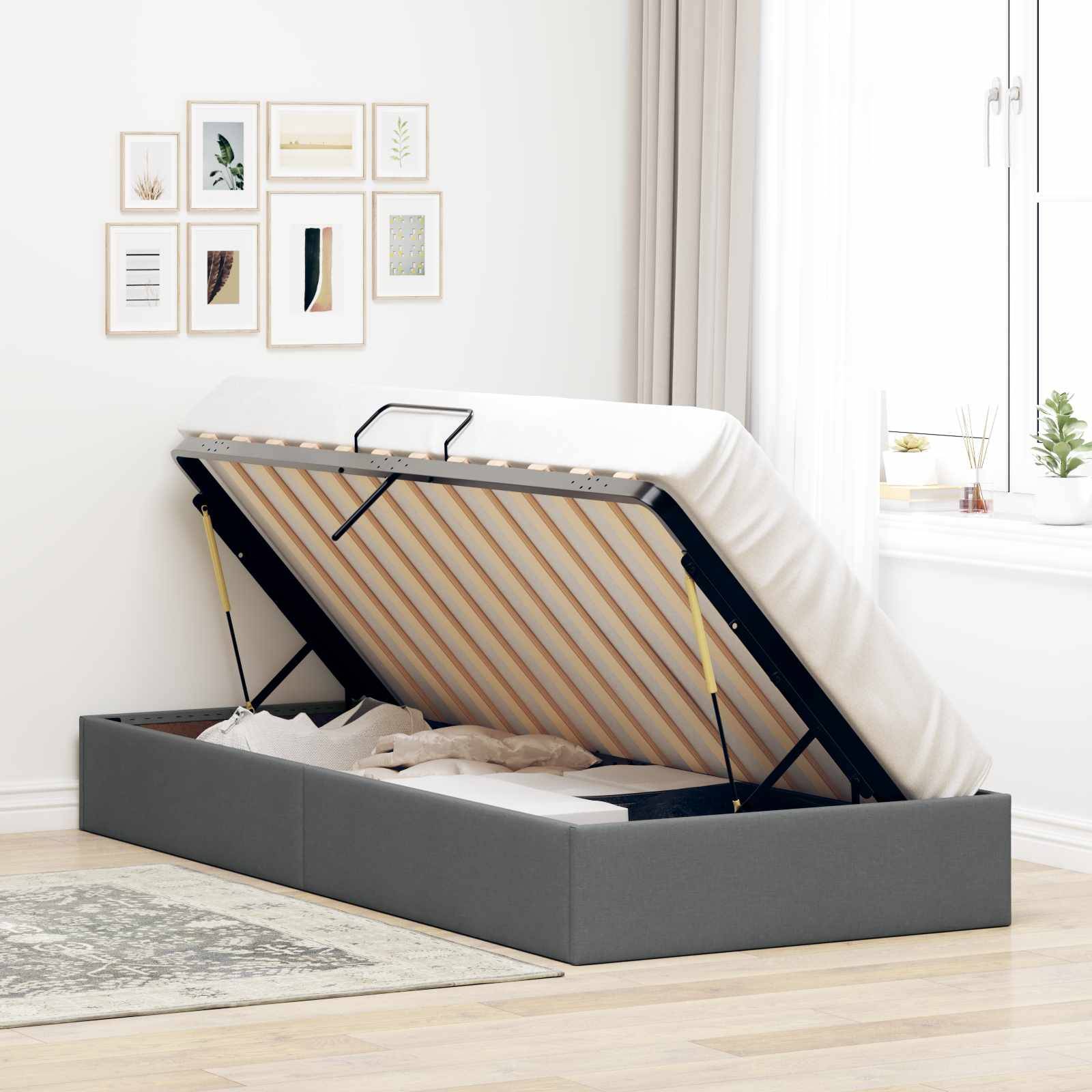 Grau gepolstertes Speicherbett mit angehobener Matratze auf einem Scharnier-Rahmen, das das Unter-Bett-Fach in einem hellen Schlafzimmer zeigt.