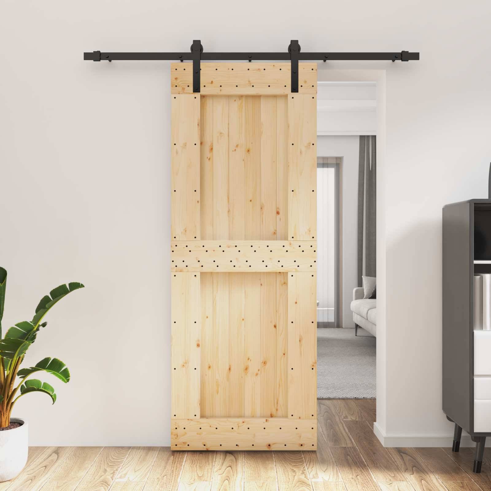 Schiebetür im Scheunenstil aus Holz auf schwarzer Schiene, teilweise offen zu einem Flur und Wohnzimmer.