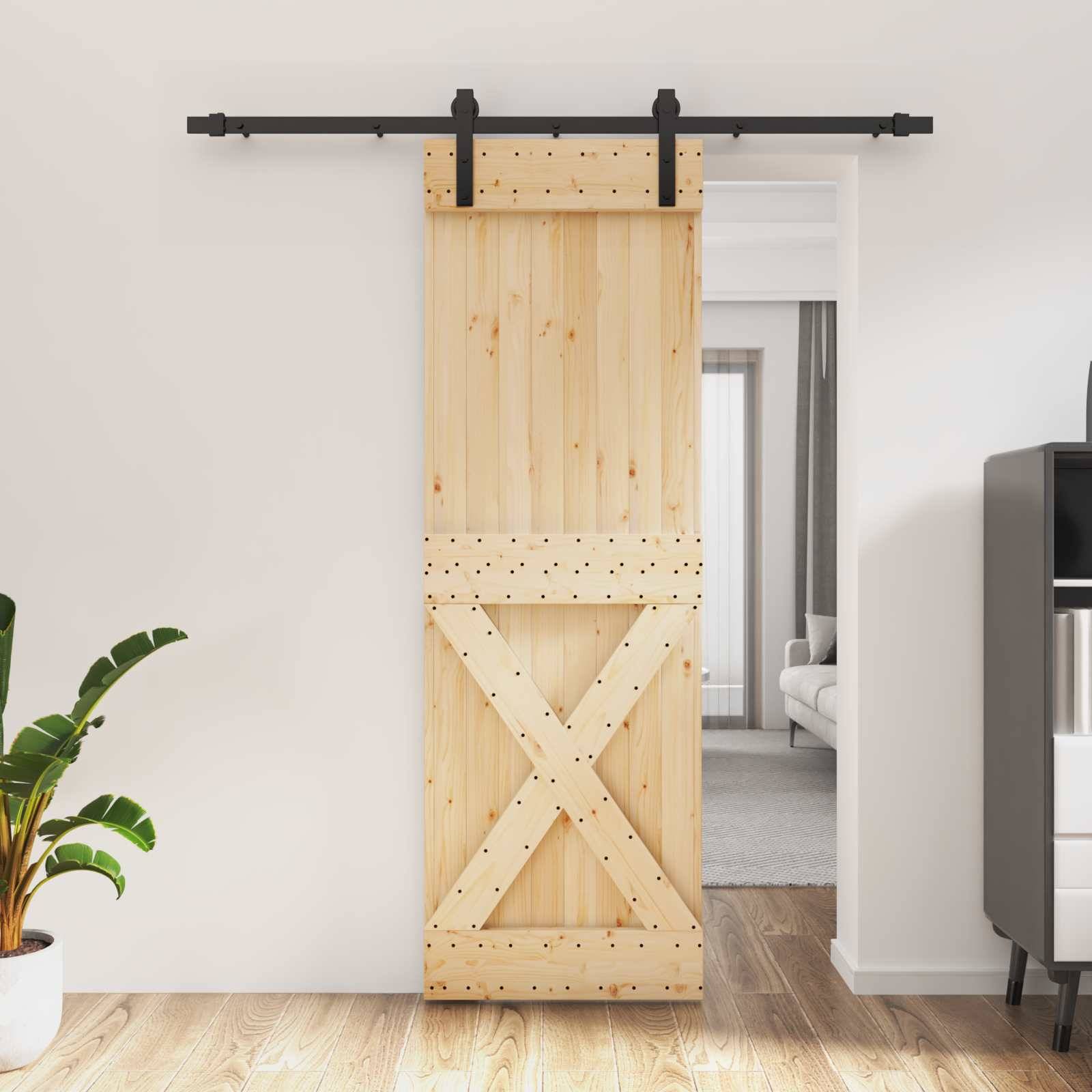 Holztür im Scheunenstil mit schwarzer Metallschiene zwischen Räumen, teilweise geöffnet zu einem Wohnbereich.