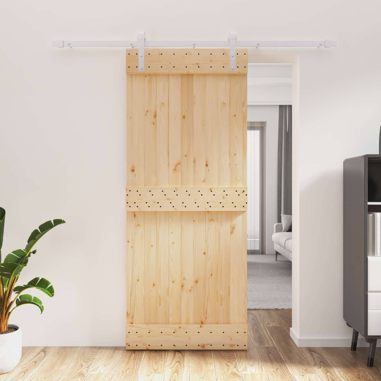 Holzschiebescheunentür teilweise offen in einem hellen modernen Innenraum, mit Blick auf einen Flur und ein Sofa dahinter.