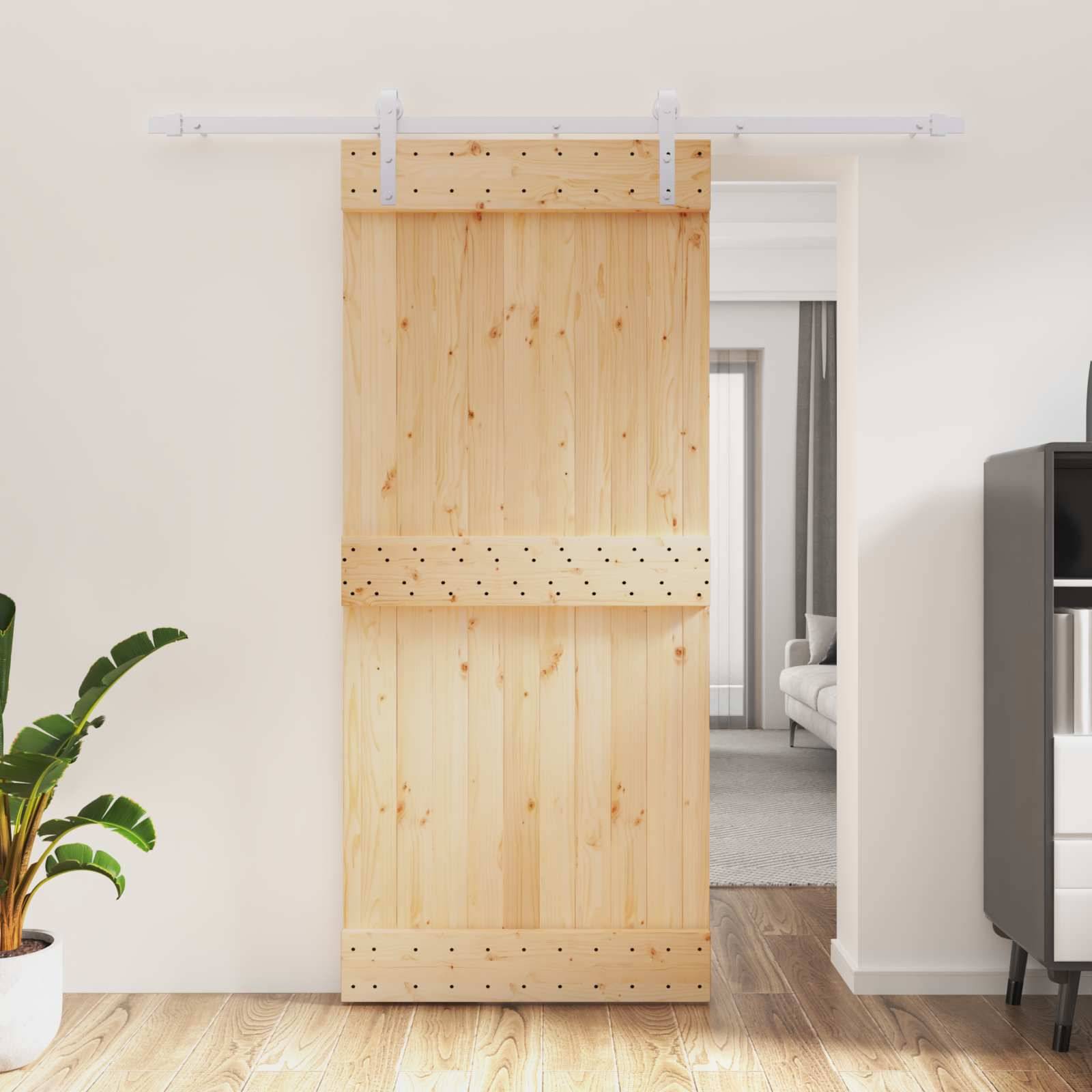 Hölzerne Scheunenschiebetür, die zwischen Räumen teilweise offen steht, in einem hellen Wohnungsinneren, mit sichtbarem Durchgang zu einem Wohnbereich dahinter.