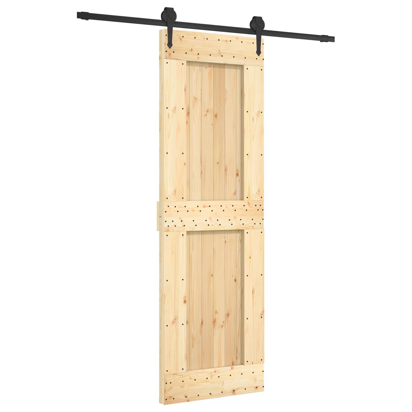 Leichte Holzscheunentürplatte, die auf einer schwarzen Schienenanlage hängt, vor einem schlichten weißen Hintergrund gezeigt.