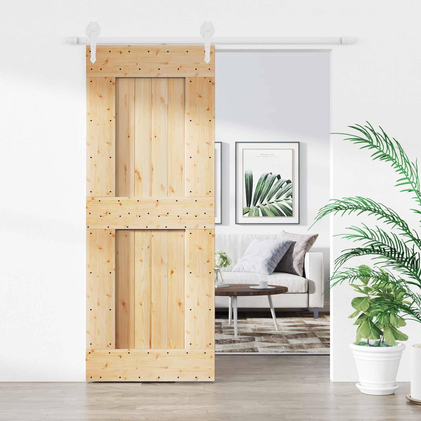 Leichte Holzschiebescheunentür auf einer Wandöffnung, die teilweise ein helles Wohnzimmer mit Sofa, Wandbild in Rahmen, Teppich und Topfpflanze enthüllt.