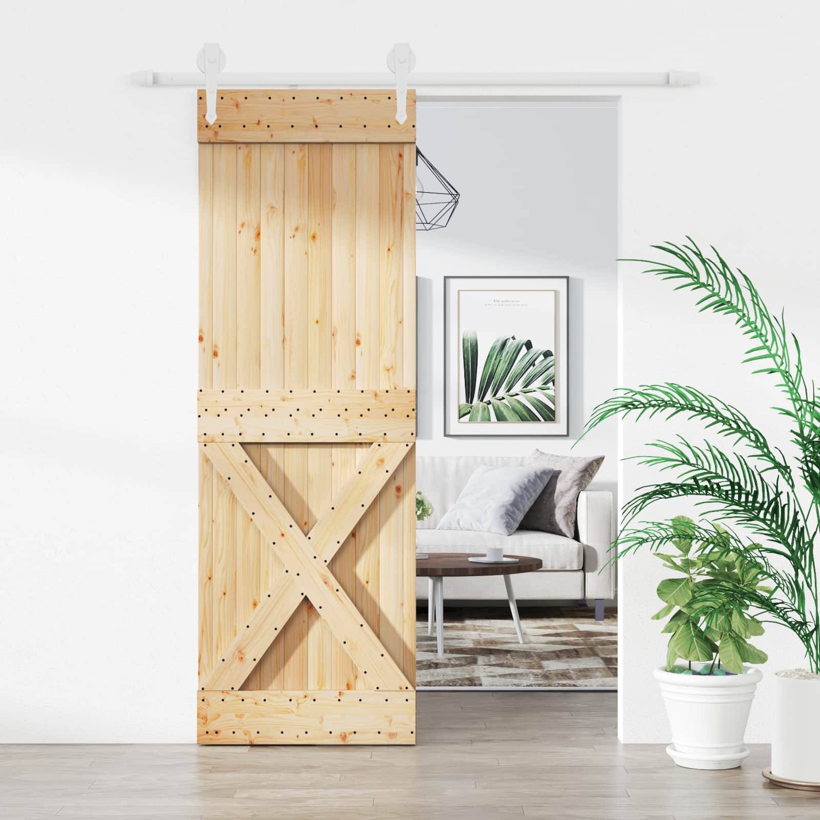 Holzschiebescheunentür, teilweise offen, mit Blick auf ein helles Wohnzimmer mit einem Sofa, einem gerahmten Blattdruck, einem Teppich und Topfpflanzen.