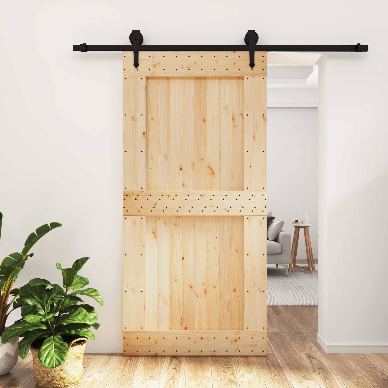 Holzschiebescheunentor teilweise offen in einem hellen Innenraum, das ein dahinter liegendes Wohnzimmer offenbart.