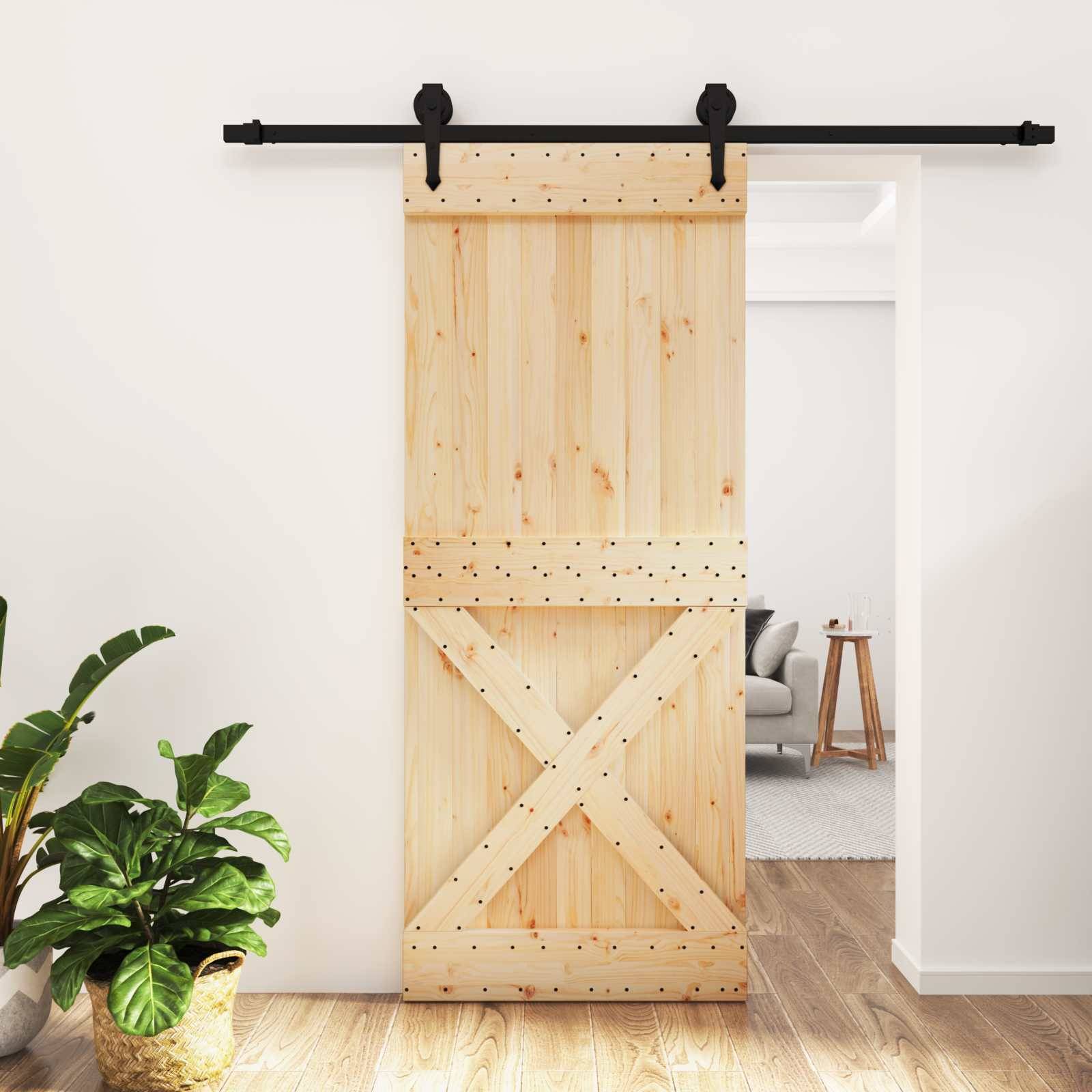 Schiebetür aus Holz an schwarzer Schiene, teilweise offen zu einem Wohnzimmer mit Sofa und Beistelltisch, in einem hellen Wohnungsinterieur.