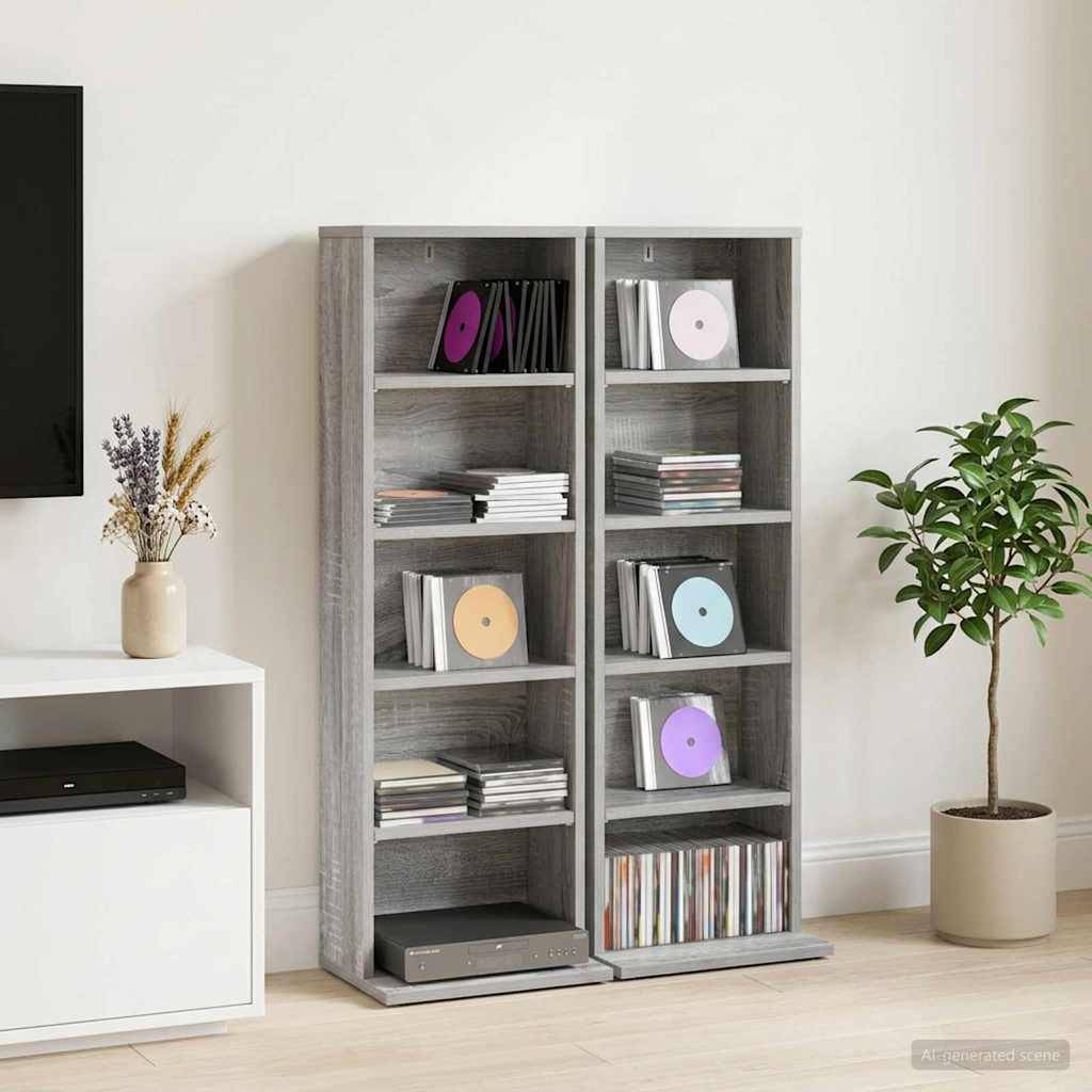 Zwei graue CD-Regale gefüllt mit Schmuckdosen und Discs, neben einem Fernsehständer, eine Vase mit Trockenblumen und ein Topfbaum in einem minimalistischen Zimmer.