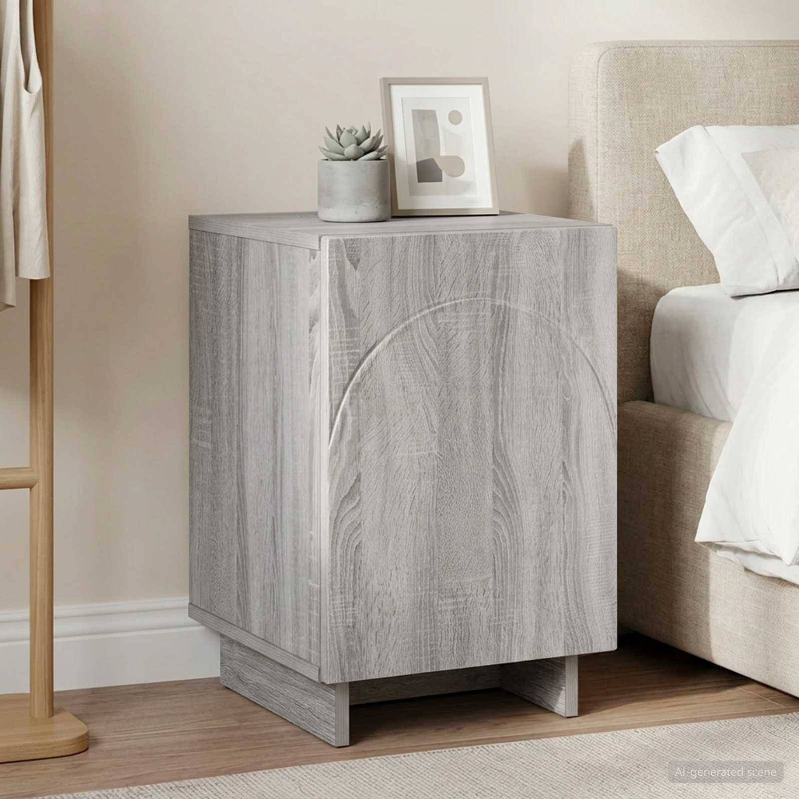 Helles Holz-Nachttischkabinett neben einem Bett, mit einer kleinen Pflanze und einem gerahmten Druck oben darauf, in einem minimalistischen Schlafzimmer.