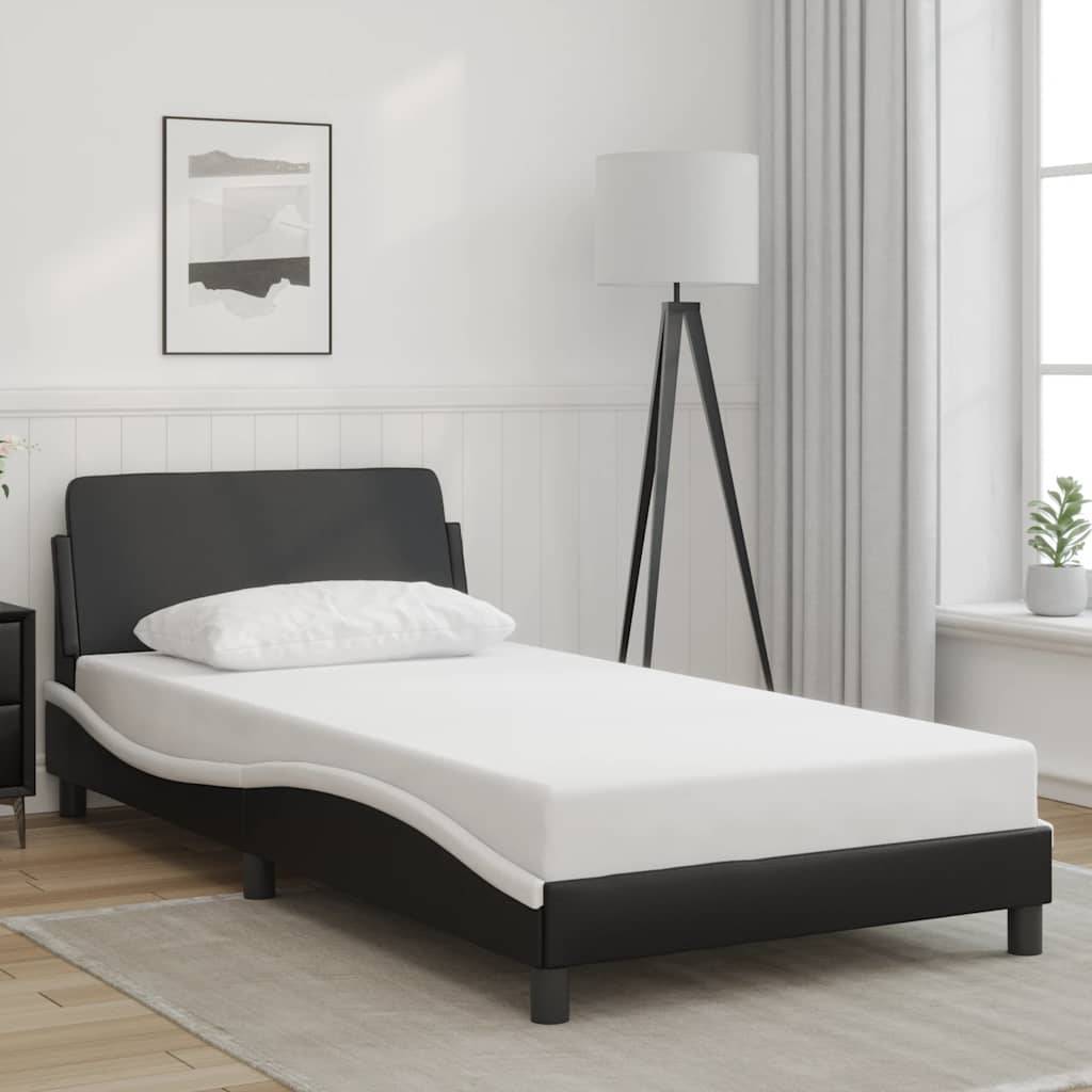 Modernes Einzelbett mit schwarzem Rahmen und weißer Matratze in einem hellen, minimalistischen Schlafzimmer neben einer Stehleuchte und einem Fenster.
