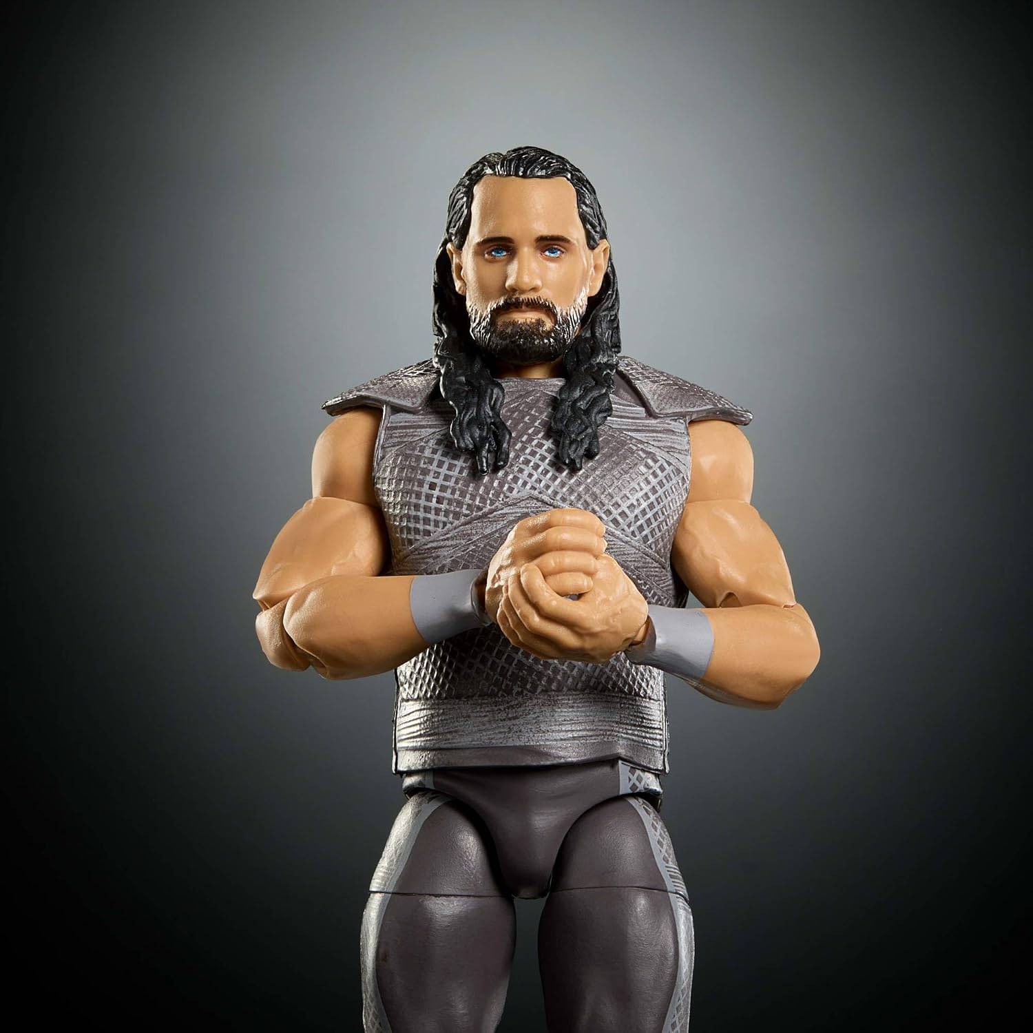 Eine muskulöse Actionfigur eines langharigen bärtigen Mannes in grauer Ringausrüstung steht mit verschränkten Händen vor einem dunklen Hintergrund.