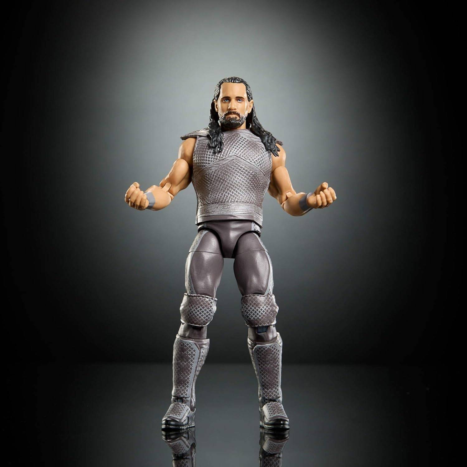 Eine gestellte Actionfigur eines muskulösen Mannes mit langen Haaren in grauer Rüstung und Stiefeln, der mit geballten Fäusten vor dunklem Studiohintergrund steht.