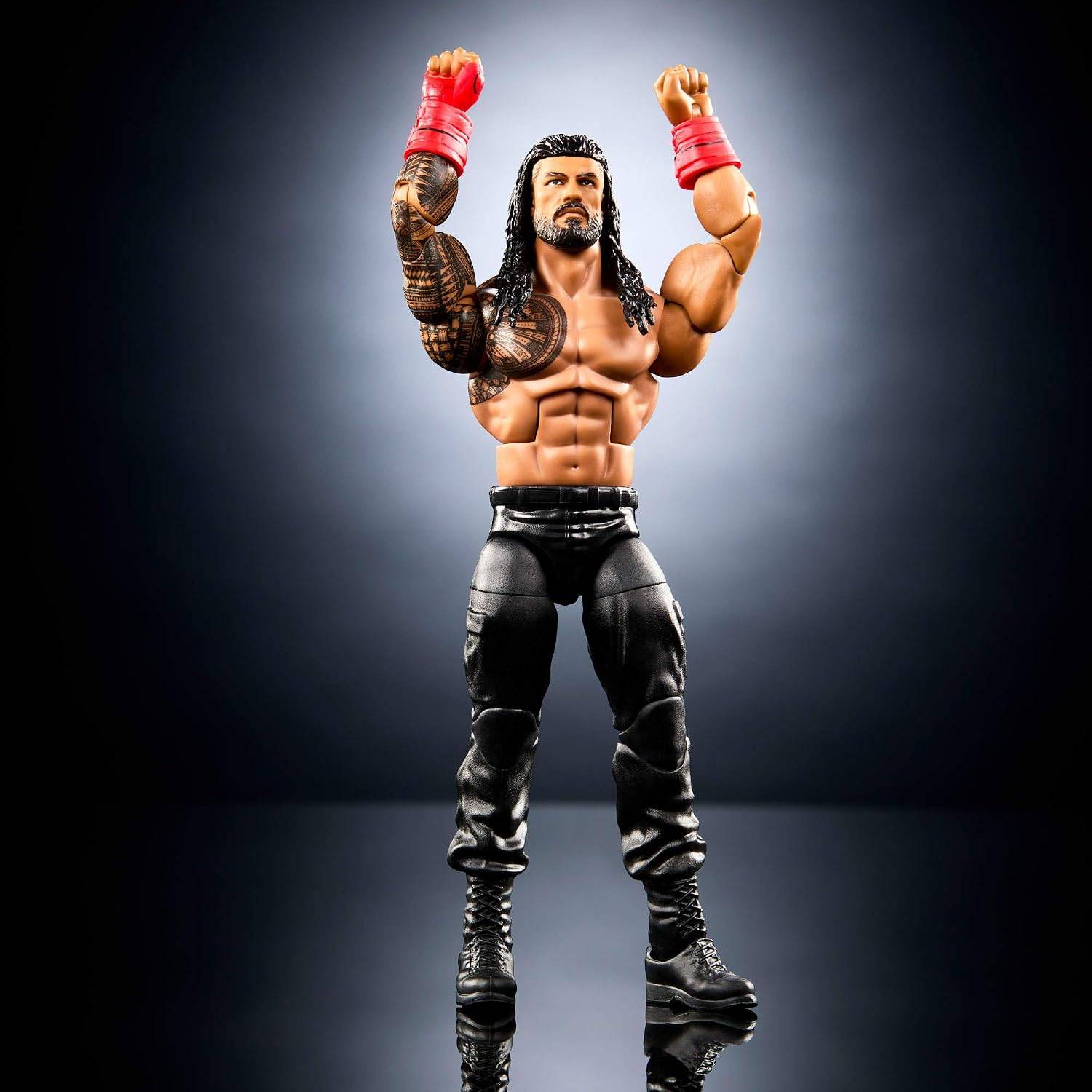 Actionfigur eines muskulösen Ringers mit langem schwarzem Haar und erhobenen Fäusten, schwarze Hosen und Stiefel tragend, rote Schweißbänder an den Handgelenken, stehend vor einem dunklen Hintergrund.