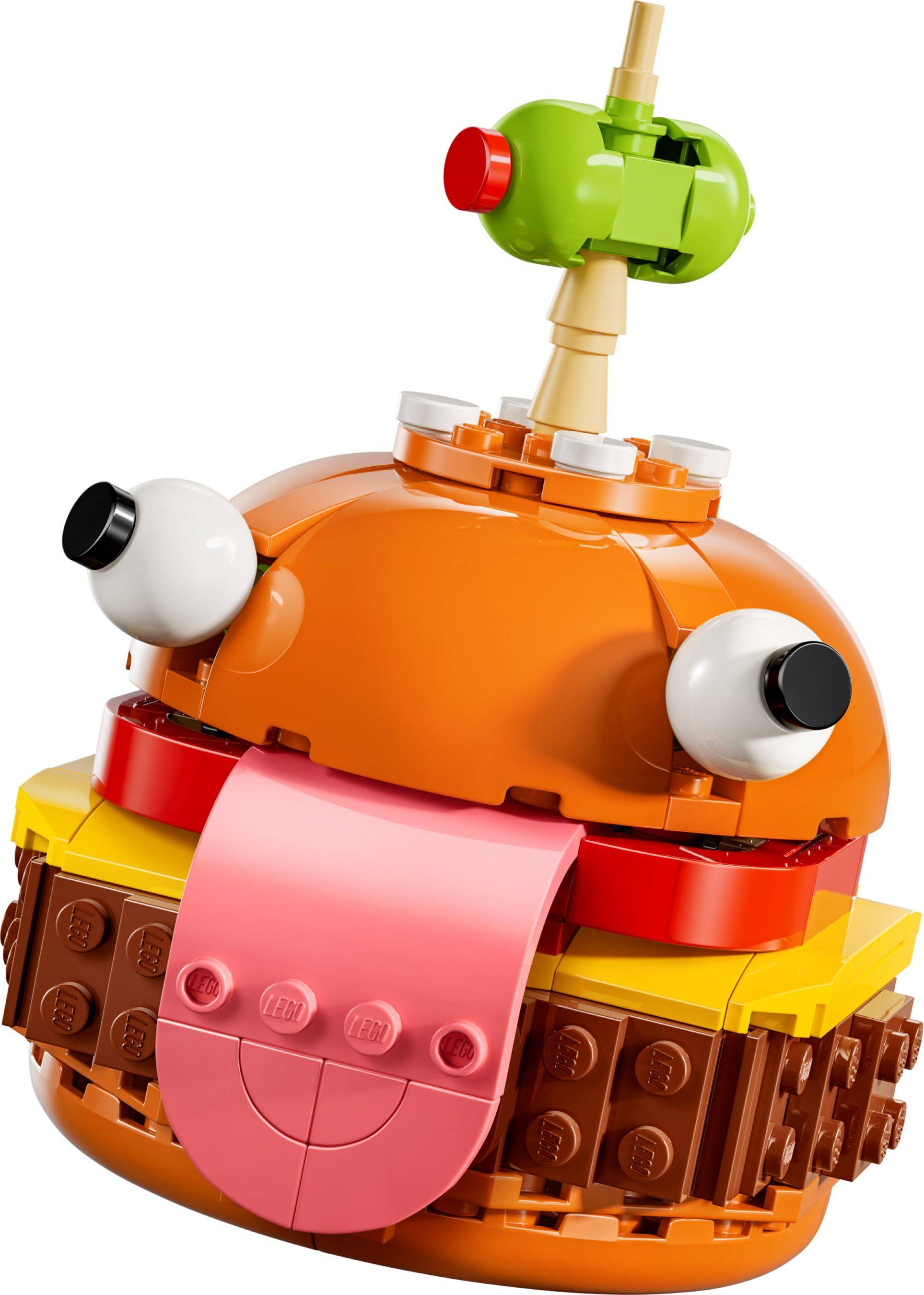 Nahaufnahme eines skurrilen LEGO-Burger-Spielzeugs mit rosa Zunge, hervorquellenden Augen und einer grünen Olive auf einem Spieß.