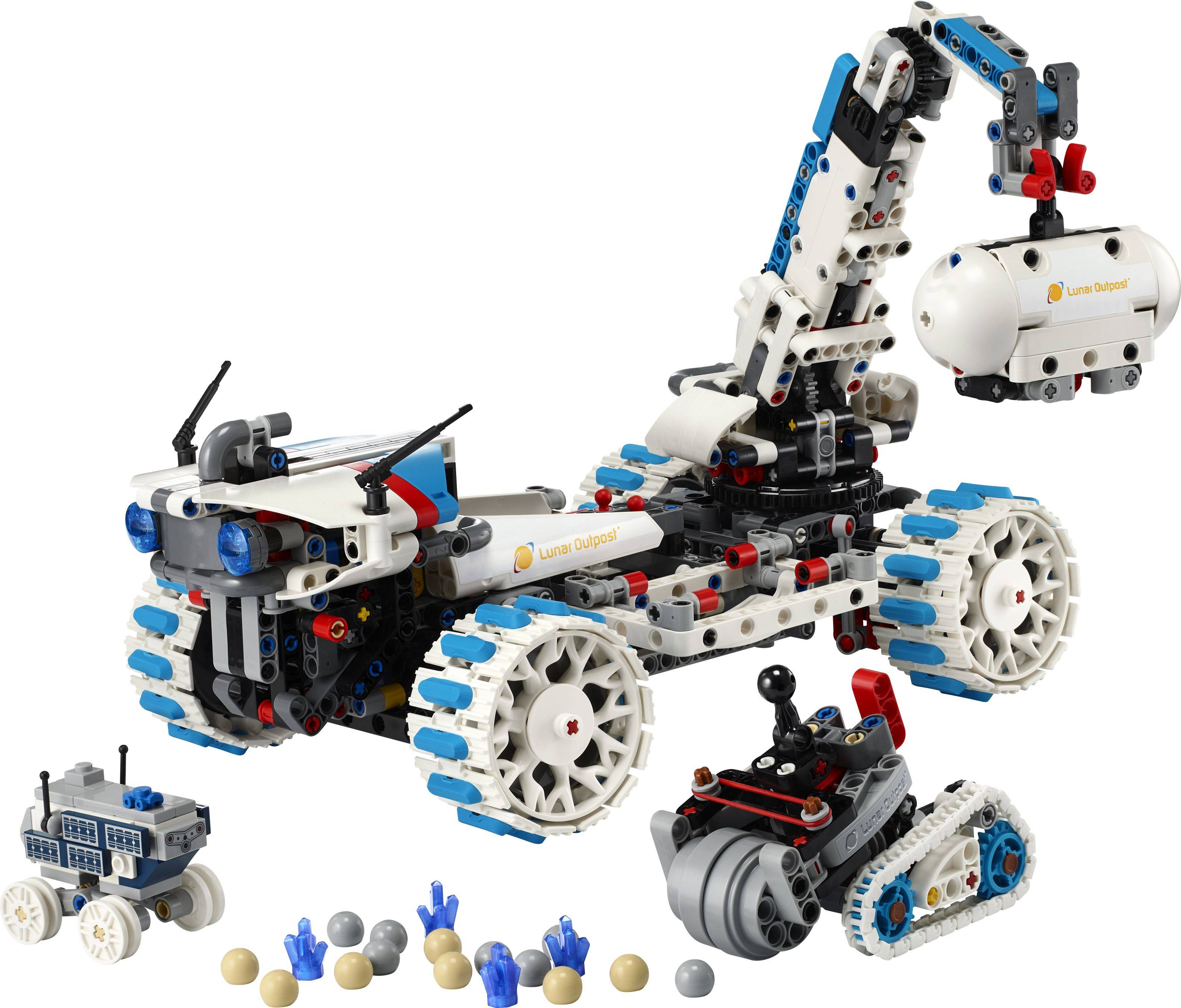 Legoähnliches robotisches Fahrzeug mit Raupen- und Radmodulen, abgebildet mit einem Roboterarm und kleinen Zubehörteilen auf weißem Hintergrund.