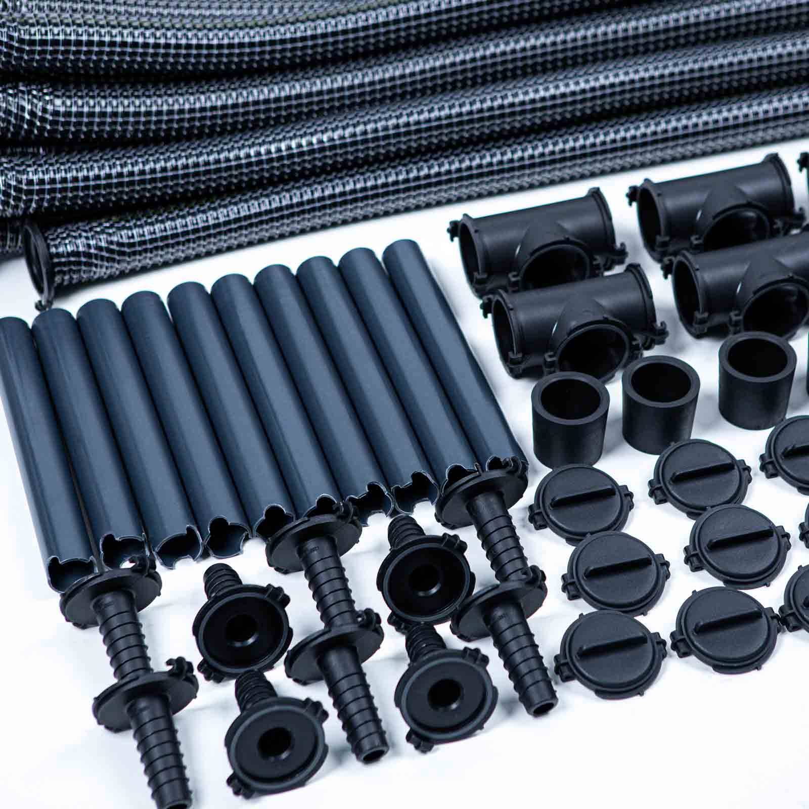 Sortierte schwarze Kunststoff-Bewässerungsteile: Tropfschläuche, Verbinder, Heringe, Endkappen und Fittings auf einer weißen Oberfläche angeordnet.
