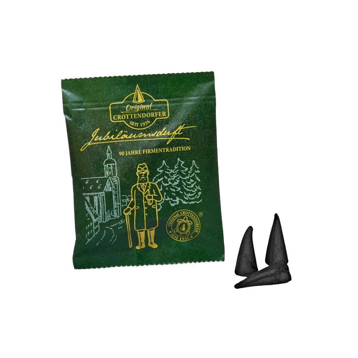 Grüne Crotendorfer Bonbonverpackung mit der Aufschrift 'Jubiläumsmint' und '90 Jahre Firmentradition' neben zwei schwarz verpackten Bonbons.