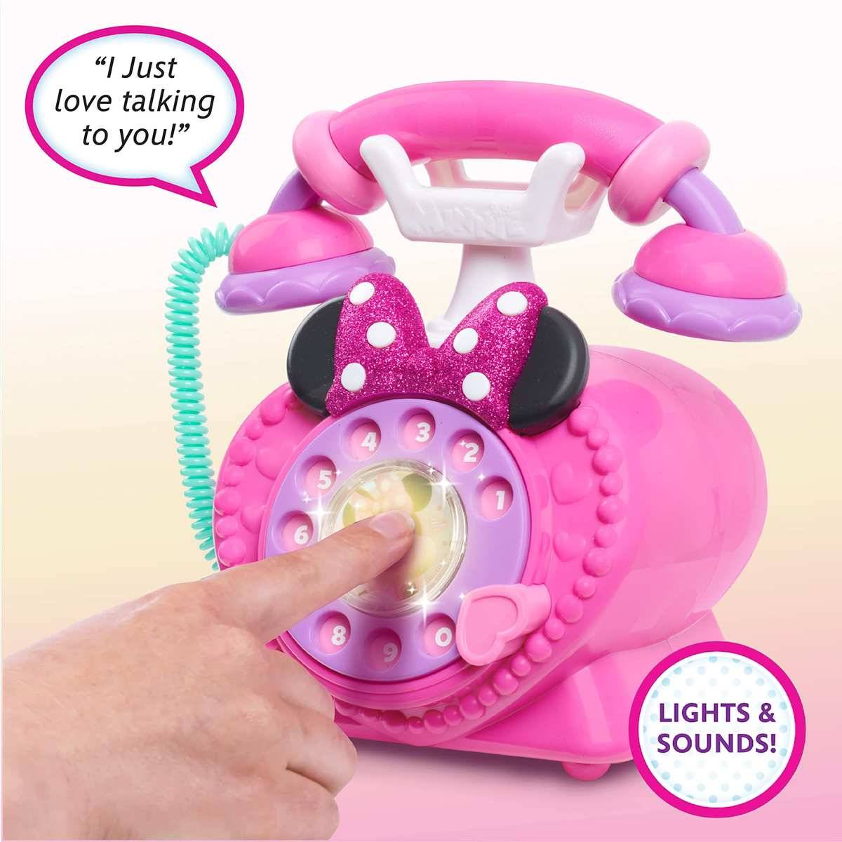 Rosa Spielzeugwählscheibentelefon im Retro-Stil mit Minnie-Maus-Ohren und Schleife, gezeigt mit einem Finger, der die Wählscheibe drückt; Beschriftungen sagen „Ich liebe es, mit dir zu sprechen!
