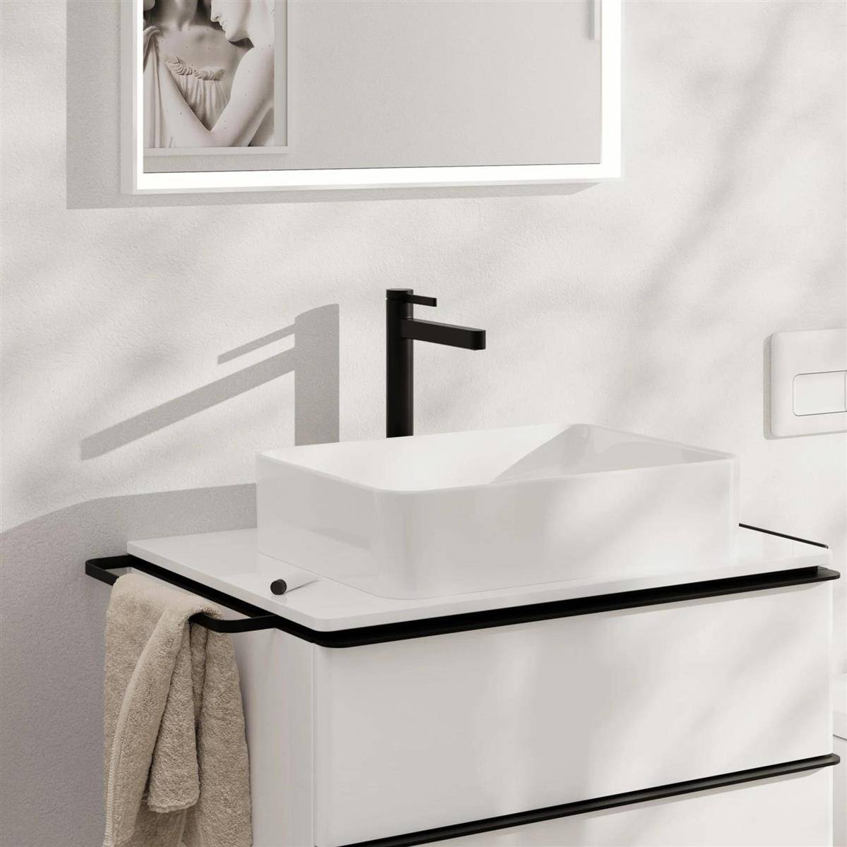 Modernes Badezimmer-Waschtischset mit weißem Becken und Schrank, schwarzem Wasserhahn und schwarzer Beschlagnahme sowie einem beigen Handtuch, das seitlich hängt.