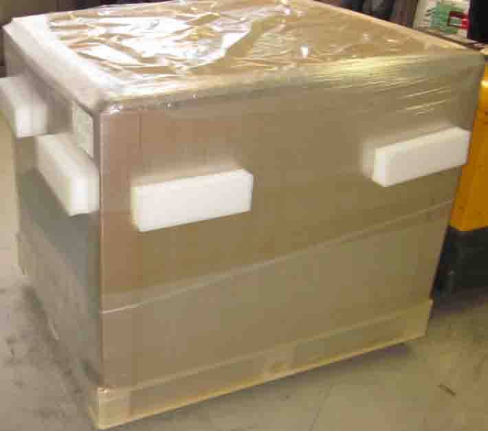 Großer schrumpffolienverpackter Kartonversandkarton auf einer Palette mit weißen Schaumstoffeckenprotektoren in einer Lagerumgebung.
