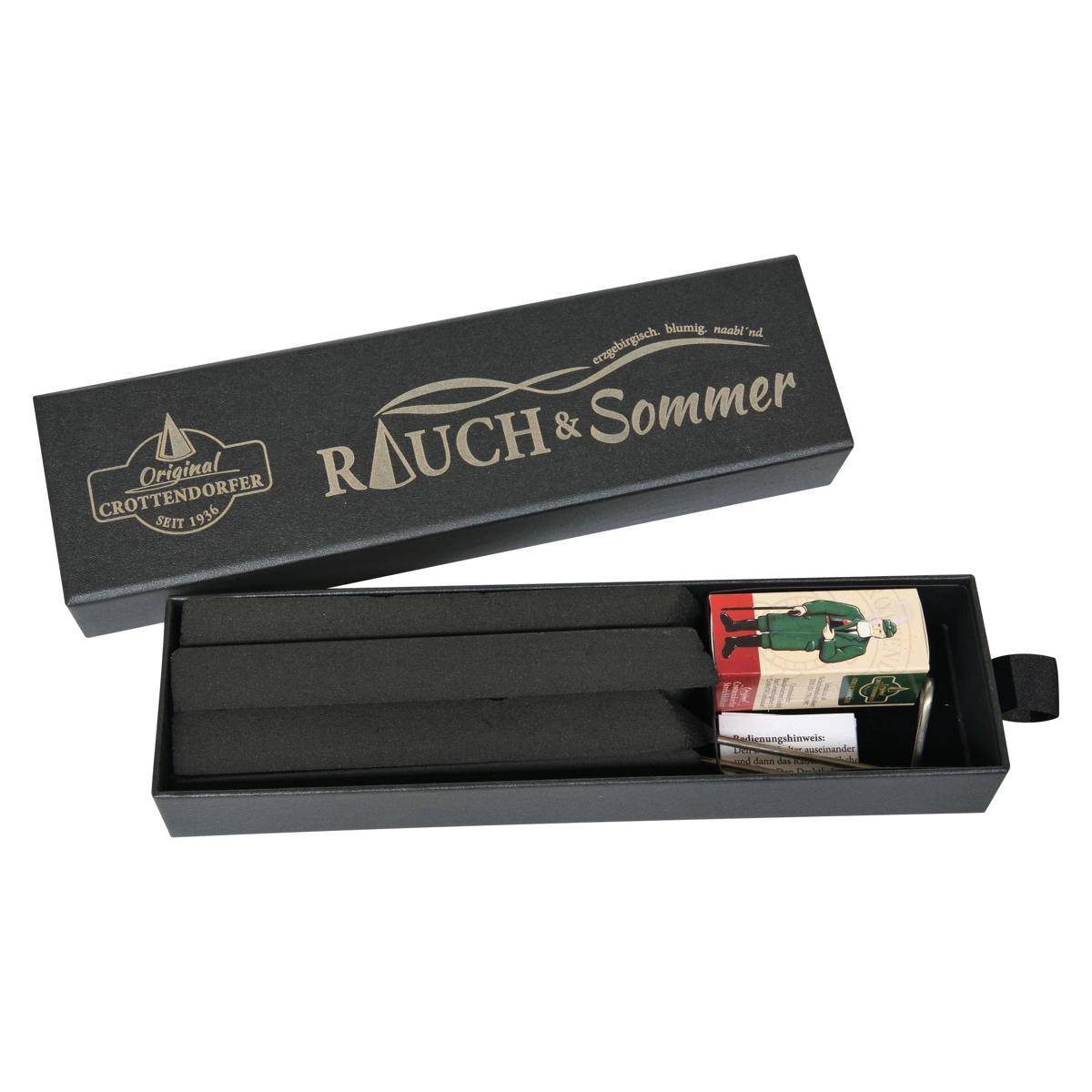 Offene schwarze Rauch & Sommer Geschenkbox mit einem schwarzen Gegenstand im Inneren und zwei kleinen Markenetiketten an einem Ende.