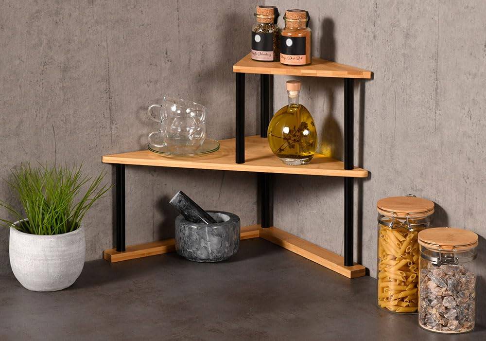 Dreiteiliges Eckregal mit Gläsern, Glaswaren, Flasche, Mörser und Stößel sowie einer Topfpflanze vor einer Betonwand.
